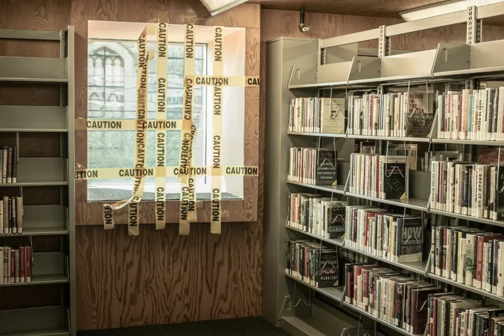 Stacks of books next to a window covered in caution tape